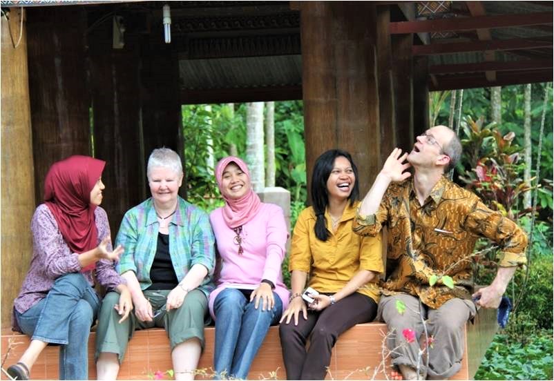 Members of ICEH's LINKS Programme sit on a bench, joking with each other