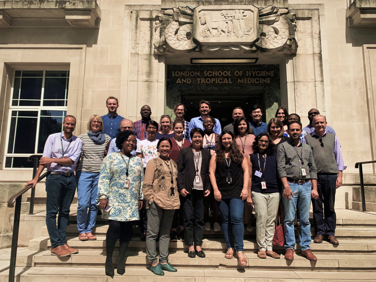 Attendees of the ICEH short course stand smiling on the steps of the school 