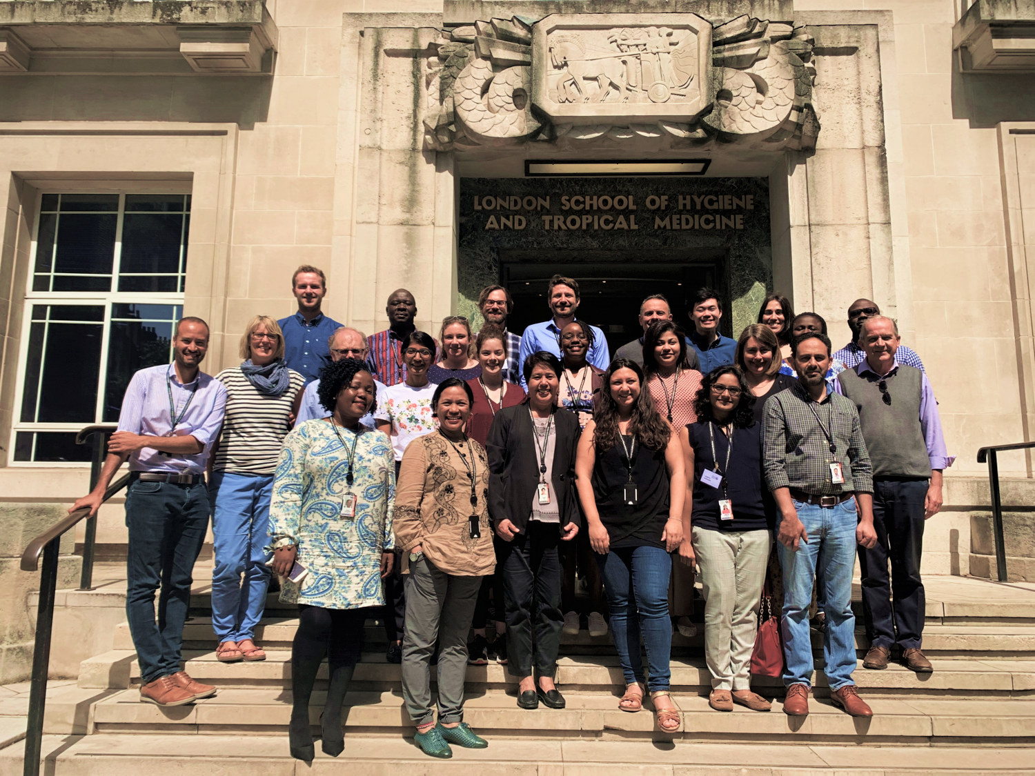 Attendees of the ICEH short course stand on the steps of the school, smiling