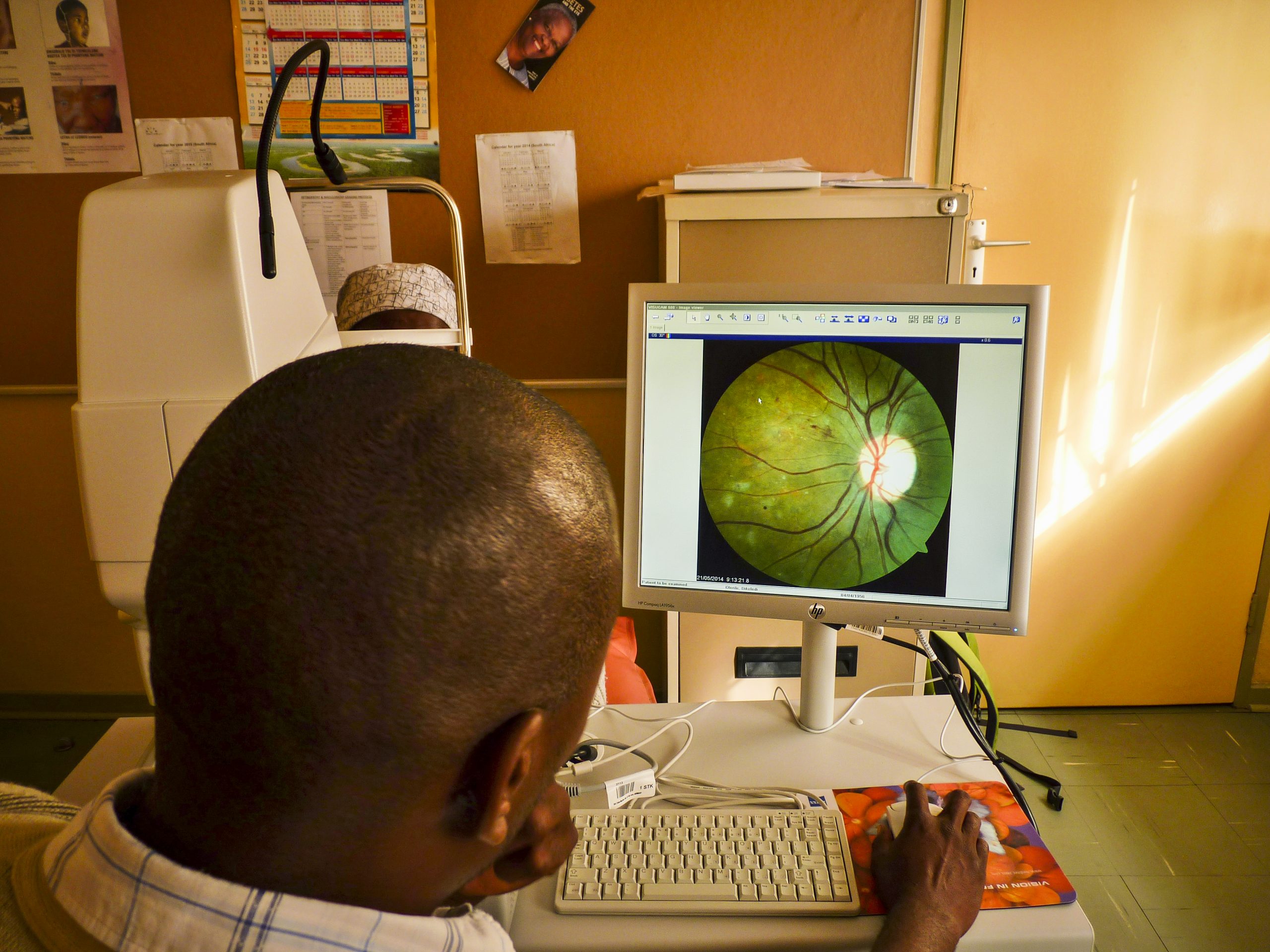 A woman in traditional robes sits on the ground following cataract surgery