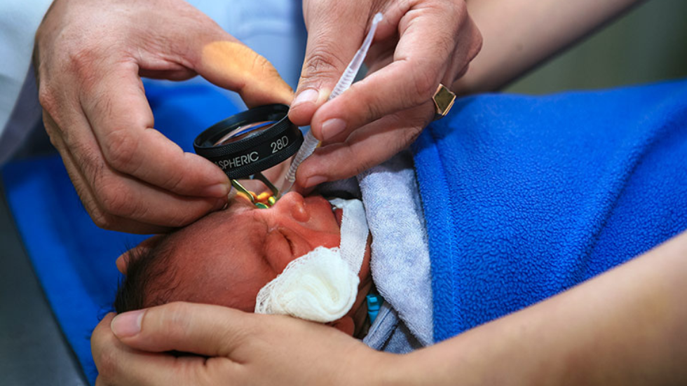 a baby has their eye examined by a lens and instrument 