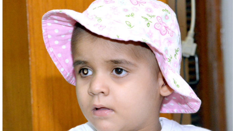 a child in a pink hat has a white reflection in one eye