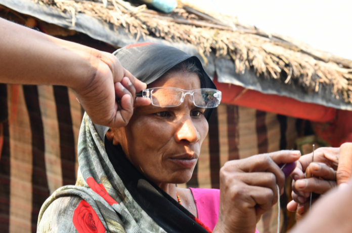 In India, a woman has glasses fitted while she sews
