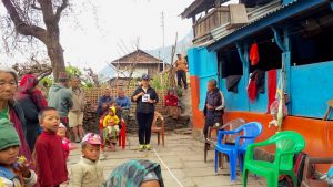 in Nepal a woman holds up a card with an 'E' for vision testing, among a group of people