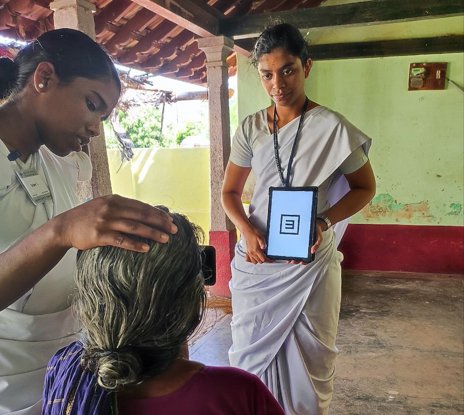A woman holds an ipad with an 'E' on it during vision testing in India