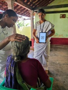 a woman holds a picture of an 'E' on a tabley in front of a seated woman