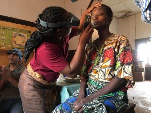 a health worker inspects a woman's eye with a torch