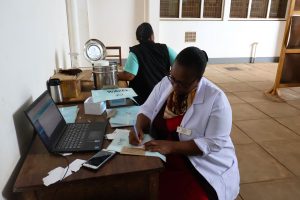 a doctor writes notes at a table in Tanzania