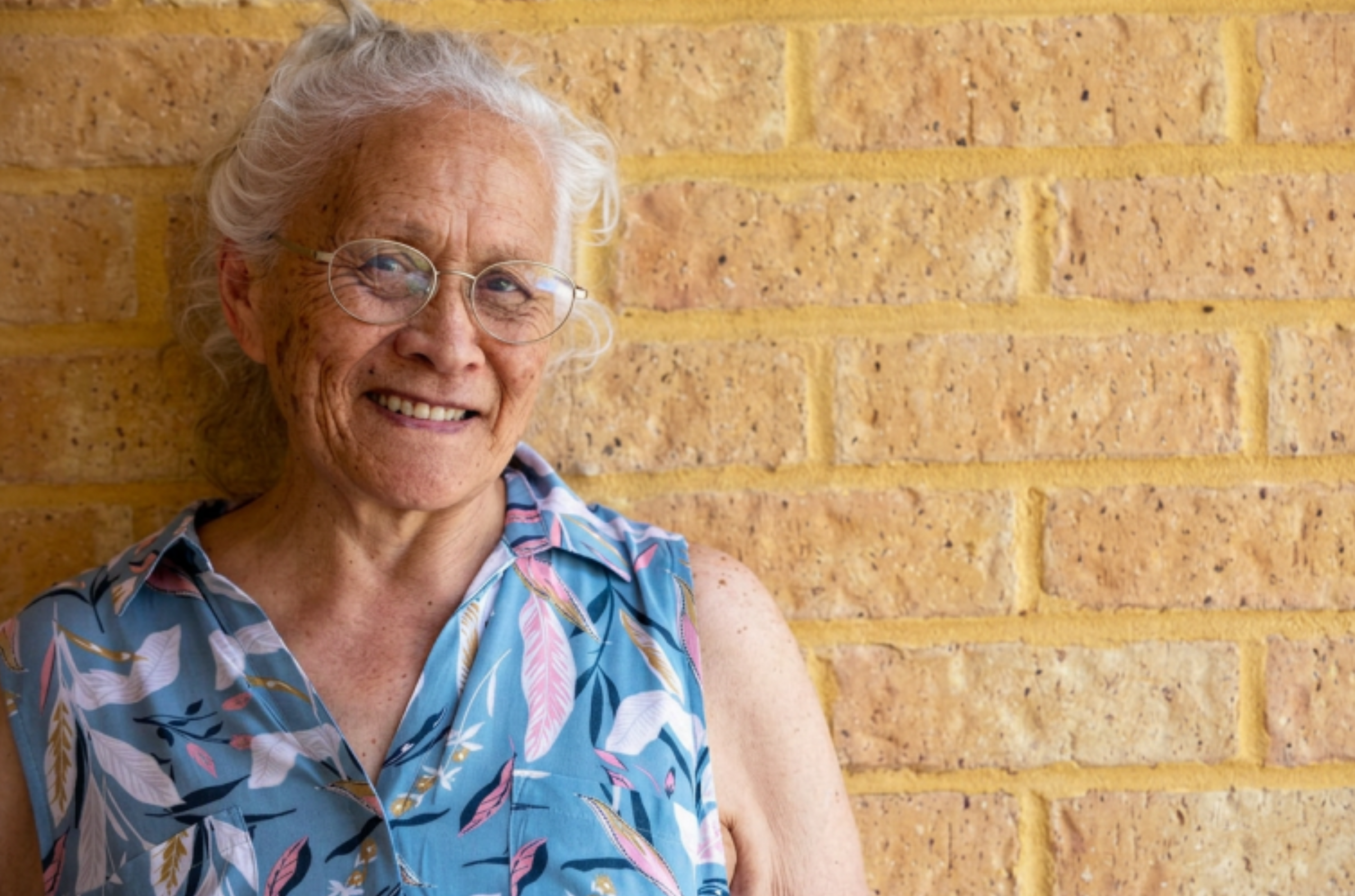 An older woman wears glasses and smiles
