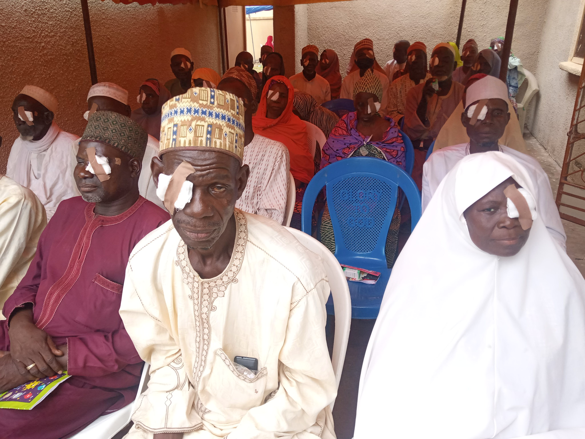 In Nigeria, patients sit in a row with bandages after cataract surgery
