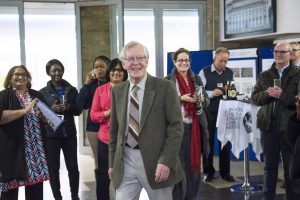 an image of Gordon Johnson walking across a crowded room with people in the background clapping