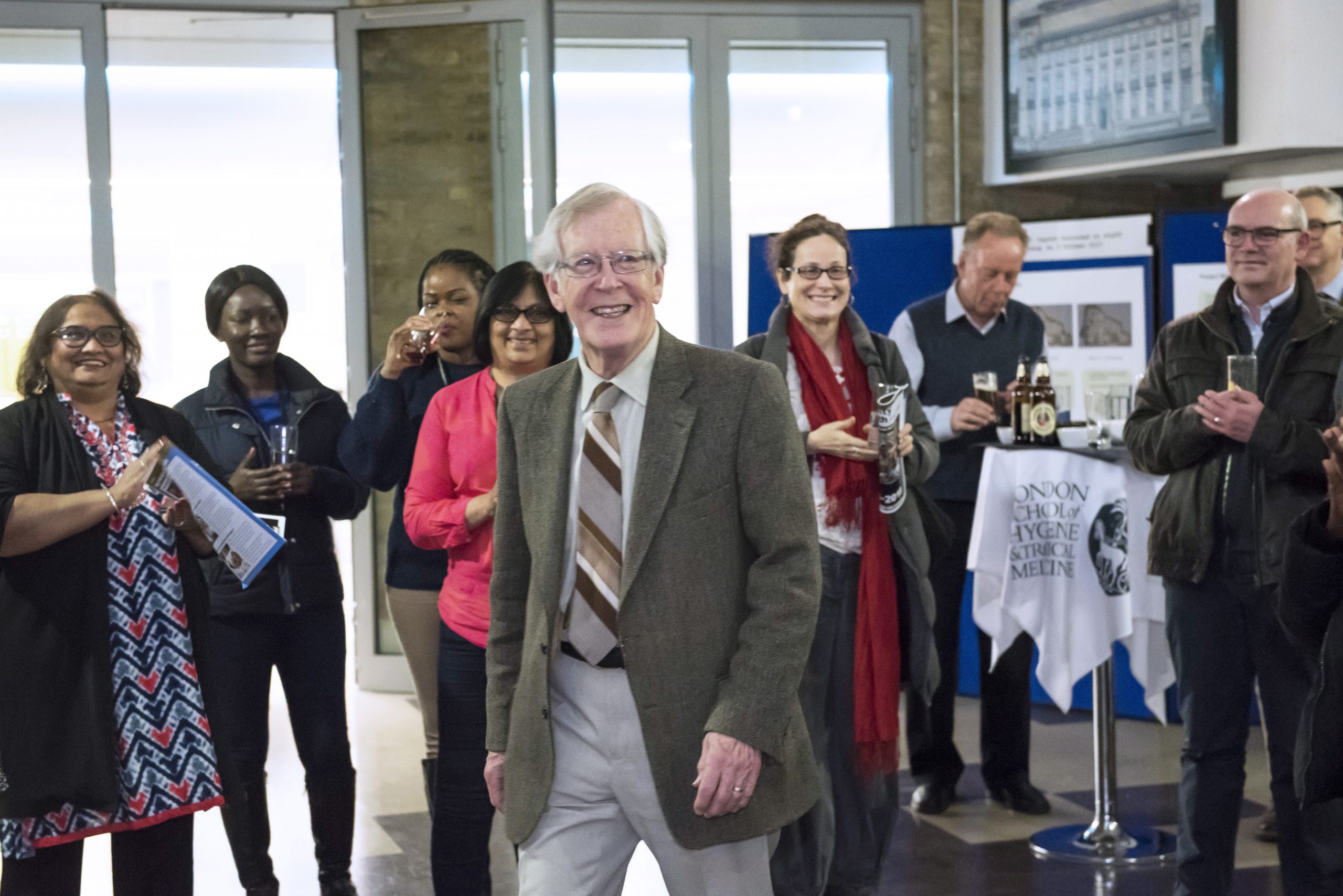 an image of Gordon Johnson walking across a crowded room with people in the background clapping