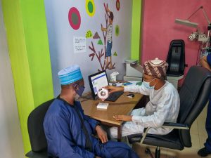 In Nigeria, a healthcare worker shows a large model of an eye to a patient at a desk
