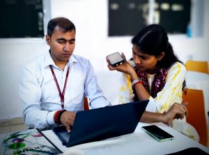 In India two health workers use a laptop and phone