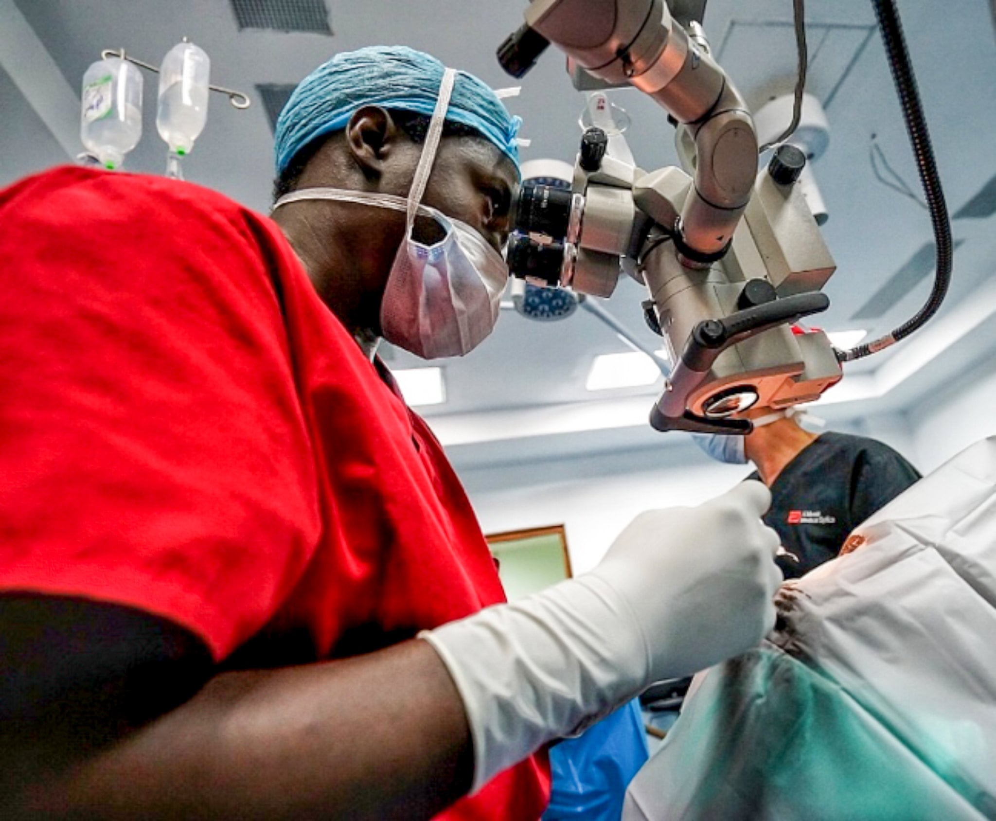 32131109897_c480ac40e5_k a surgeon in a red gown performs cataract surgery