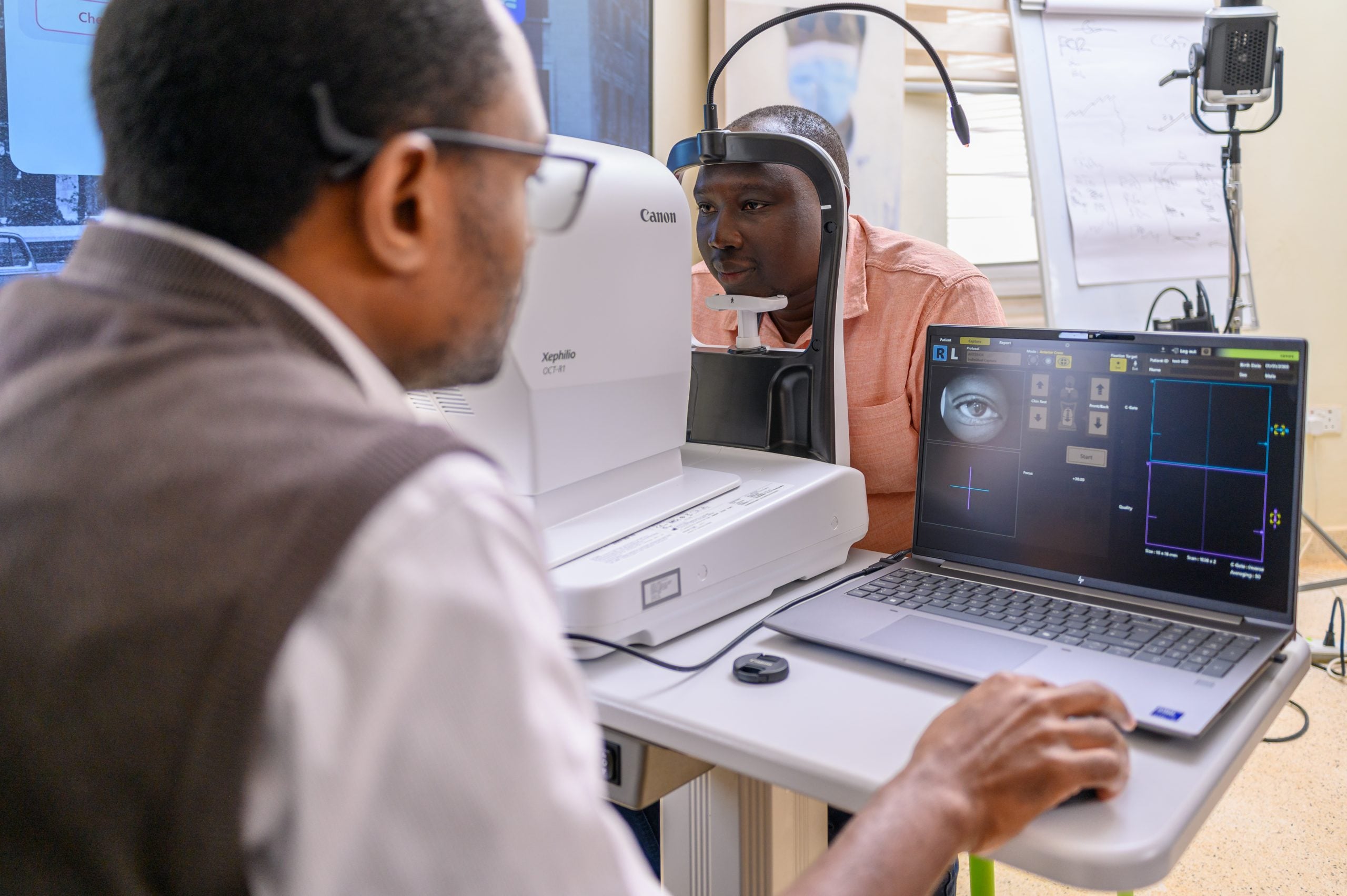 a man sits at an OCT eye machine for an eye test