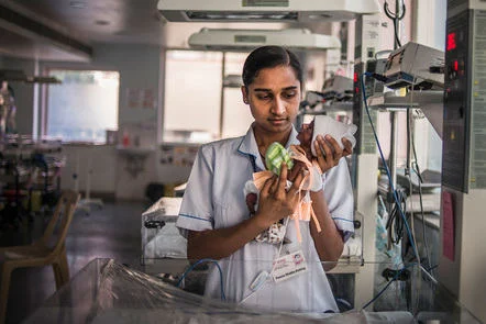 a nurse holds a premature baby on a ward
