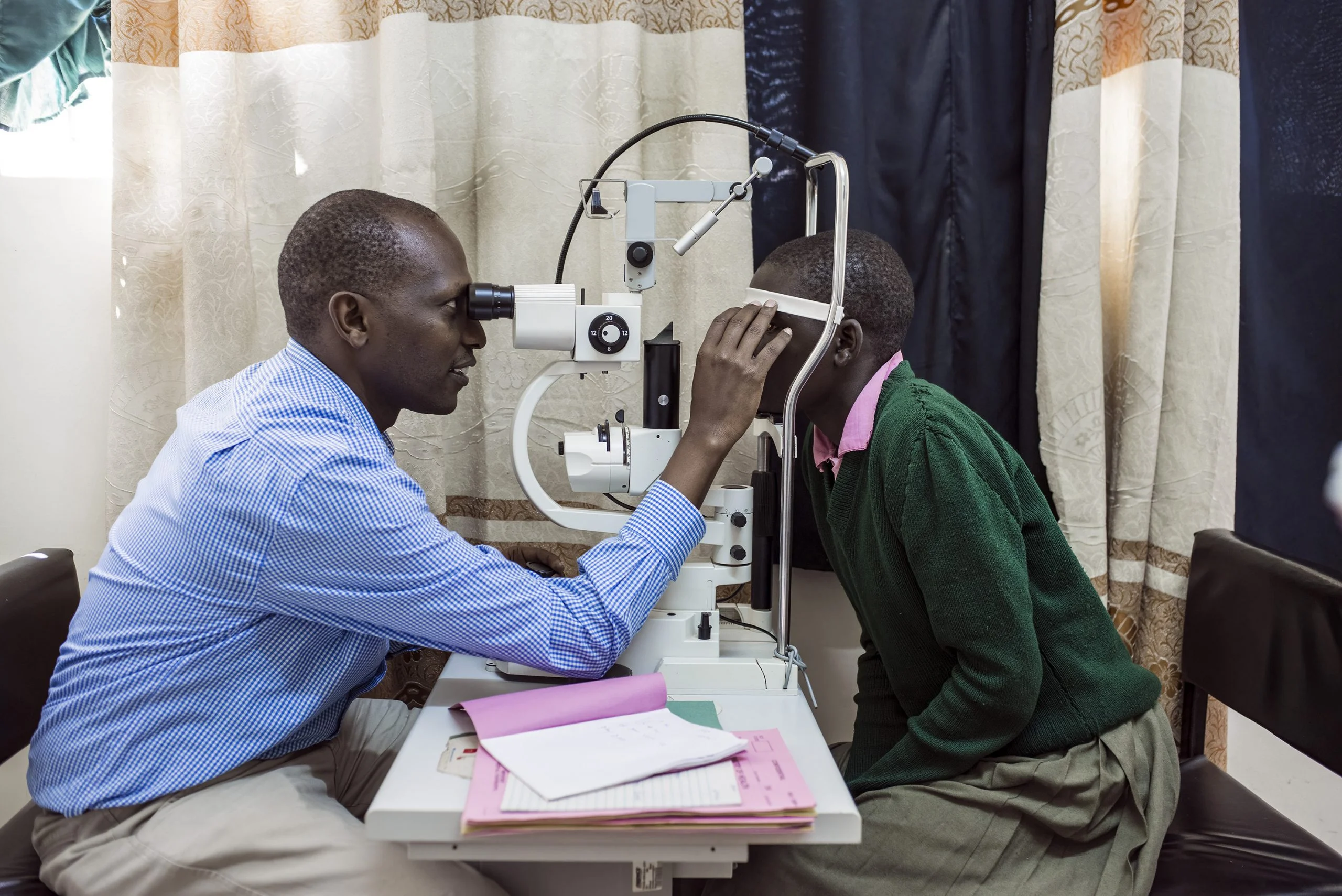 a girl is examined at a slit lamp by a doctor